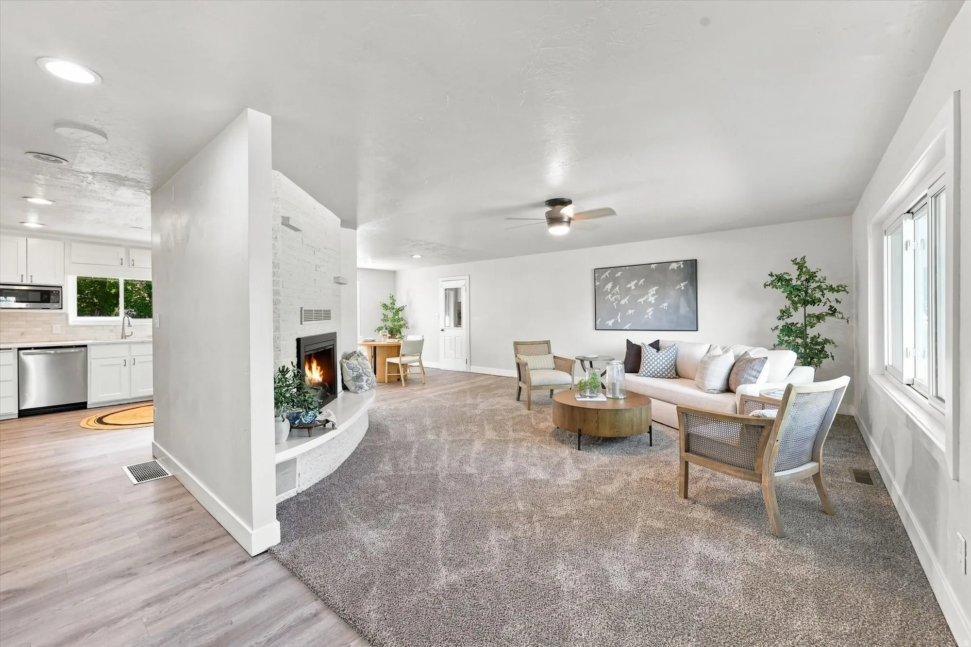 Open concept living area featuring a central fireplace with a curved hearth, recessed lighting, and a ceiling fan