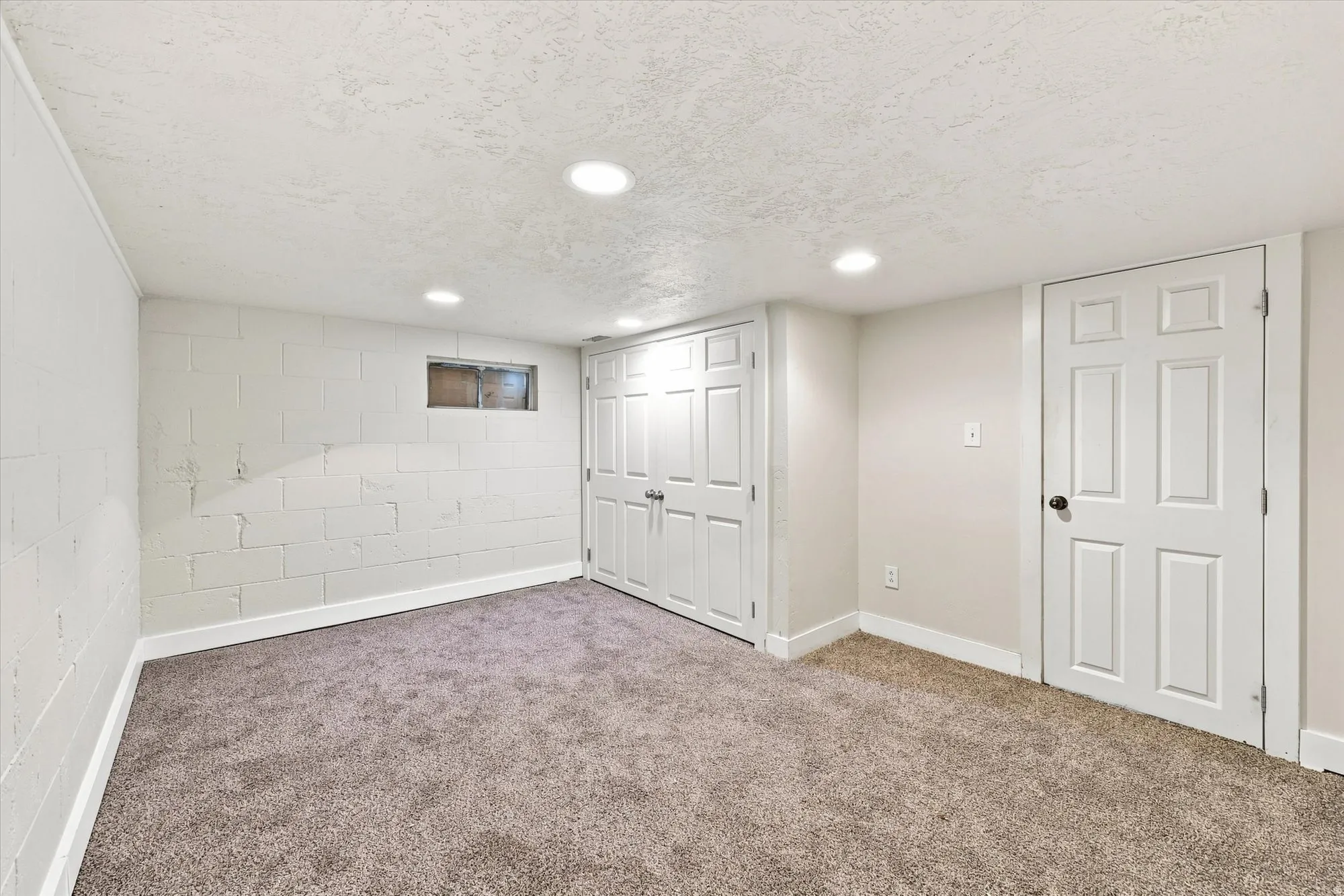 Recessed ceiling lighting, textured ceiling, light-colored walls, carpet flooring, and white trim throughout