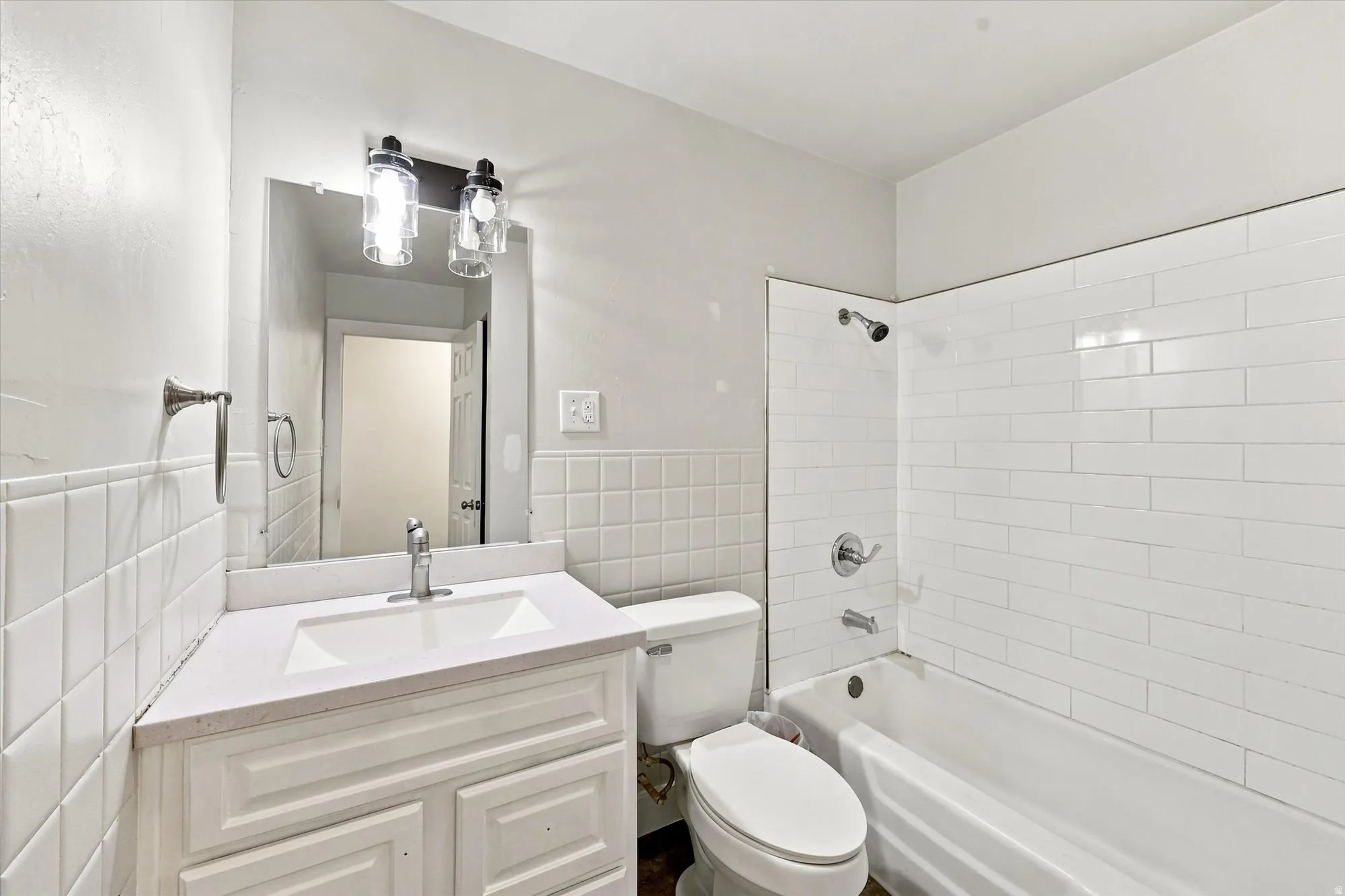 Bathroom featuring a white vanity with an integrated sink, polished chrome faucet, and quartz countertop