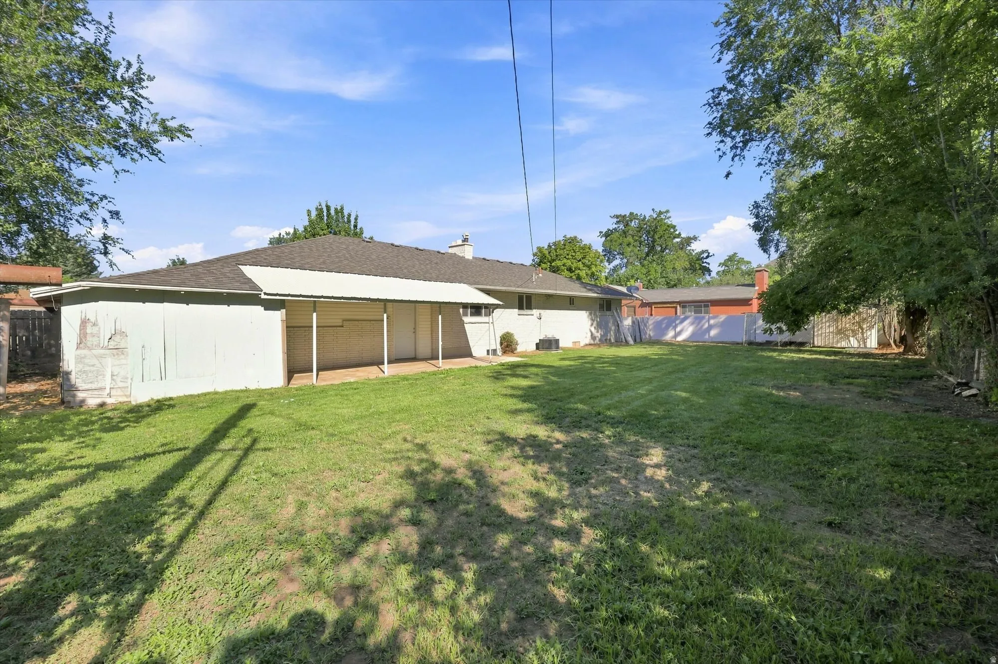 Spacious lawn with a white vinyl privacy fence and a rear covered patio