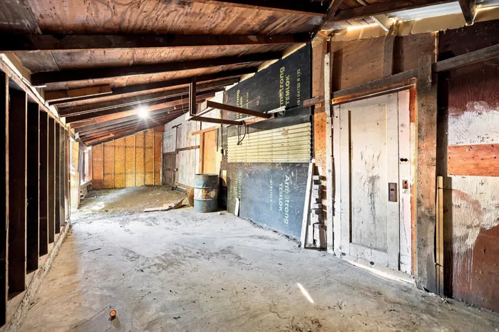 Exposed wood beam ceiling, concrete flooring, and unfinished wall studs