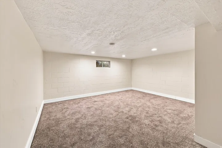 Carpeted room with recessed ceiling lighting, a window, and painted block walls