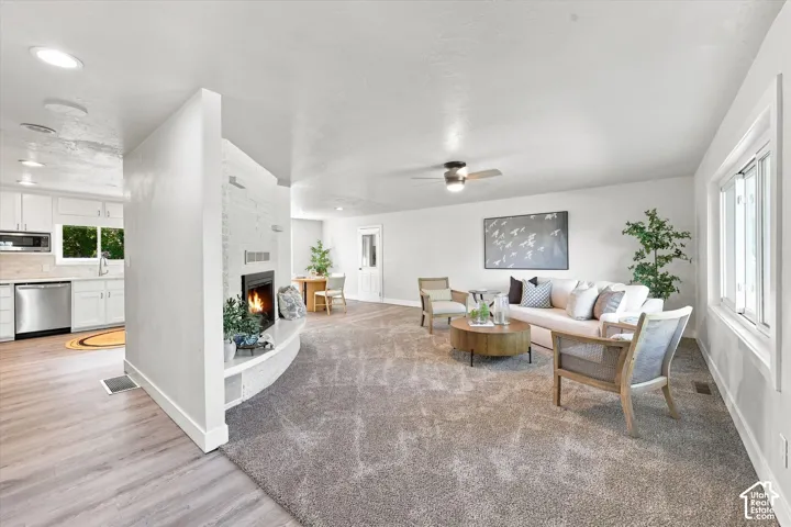 Open concept living area featuring a central fireplace with a curved hearth, recessed lighting, and a ceiling fan