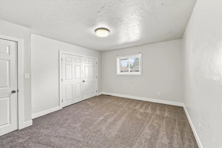 Neutral wall finishes, recessed window, flush-mount ceiling light, and bi-fold closet doors