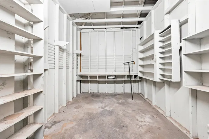 Extensive built-in shelving, concrete flooring, exposed ceiling joists, and a horizontal slatted wall panel