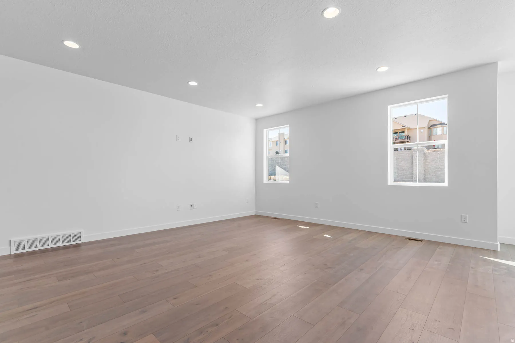 Recessed lighting, wood-finish flooring, and white walls