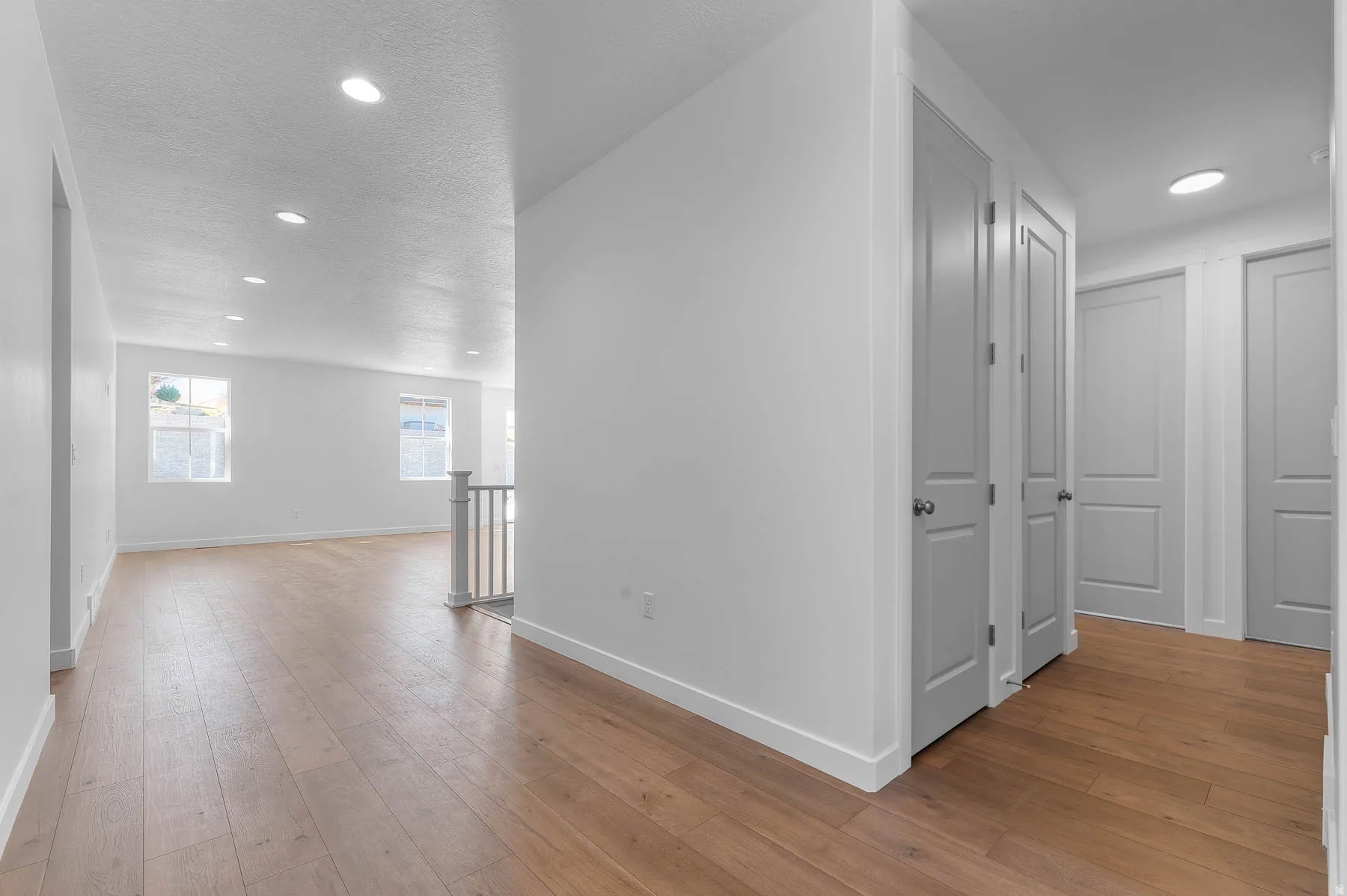 Wood-finish flooring throughout, recessed lighting, and multiple interior doors