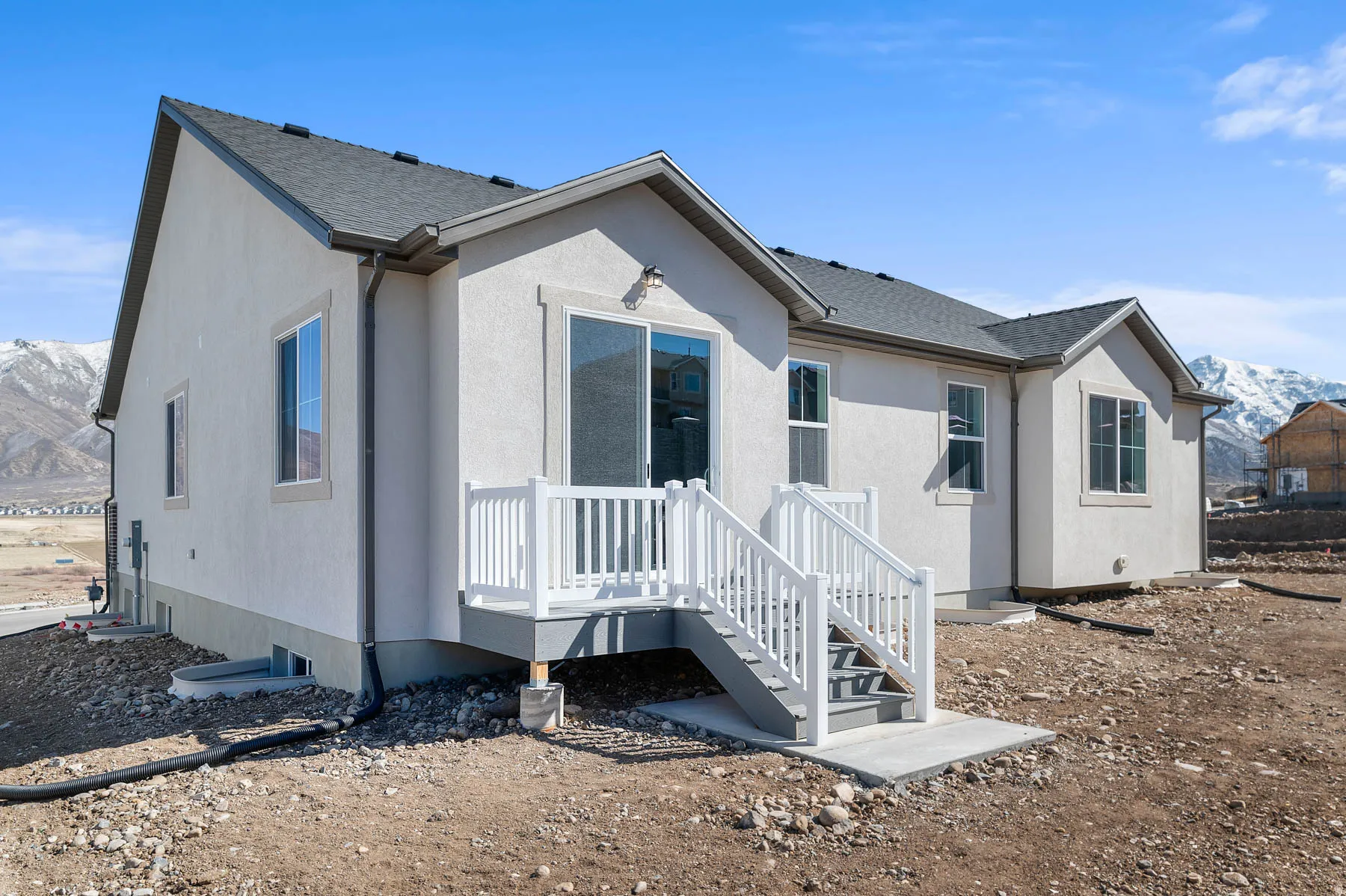 Neutral-toned stucco exterior with a dark shingle roof