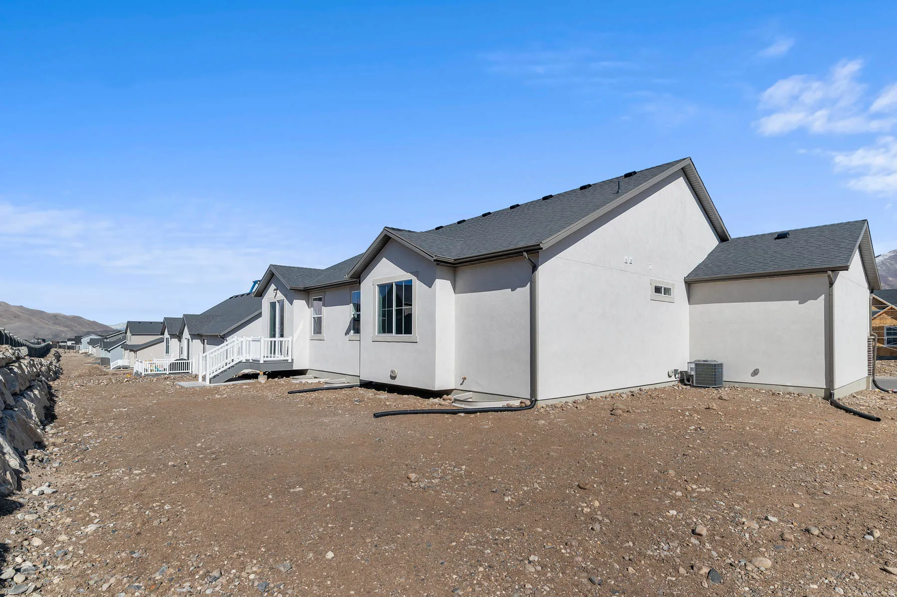 Exterior featuring stucco siding, multi-pane windows, and a dark shingle roof