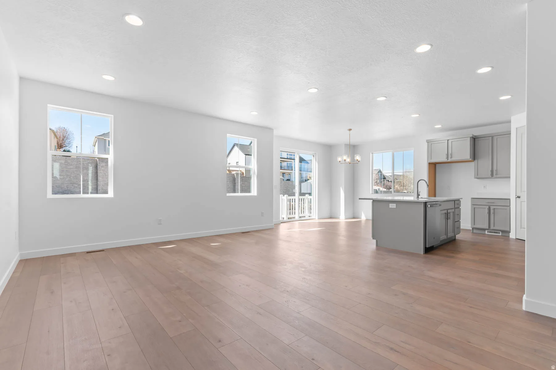 Open-concept living area featuring wood-finish flooring, recessed lighting, and a kitchen island with integrated sink
