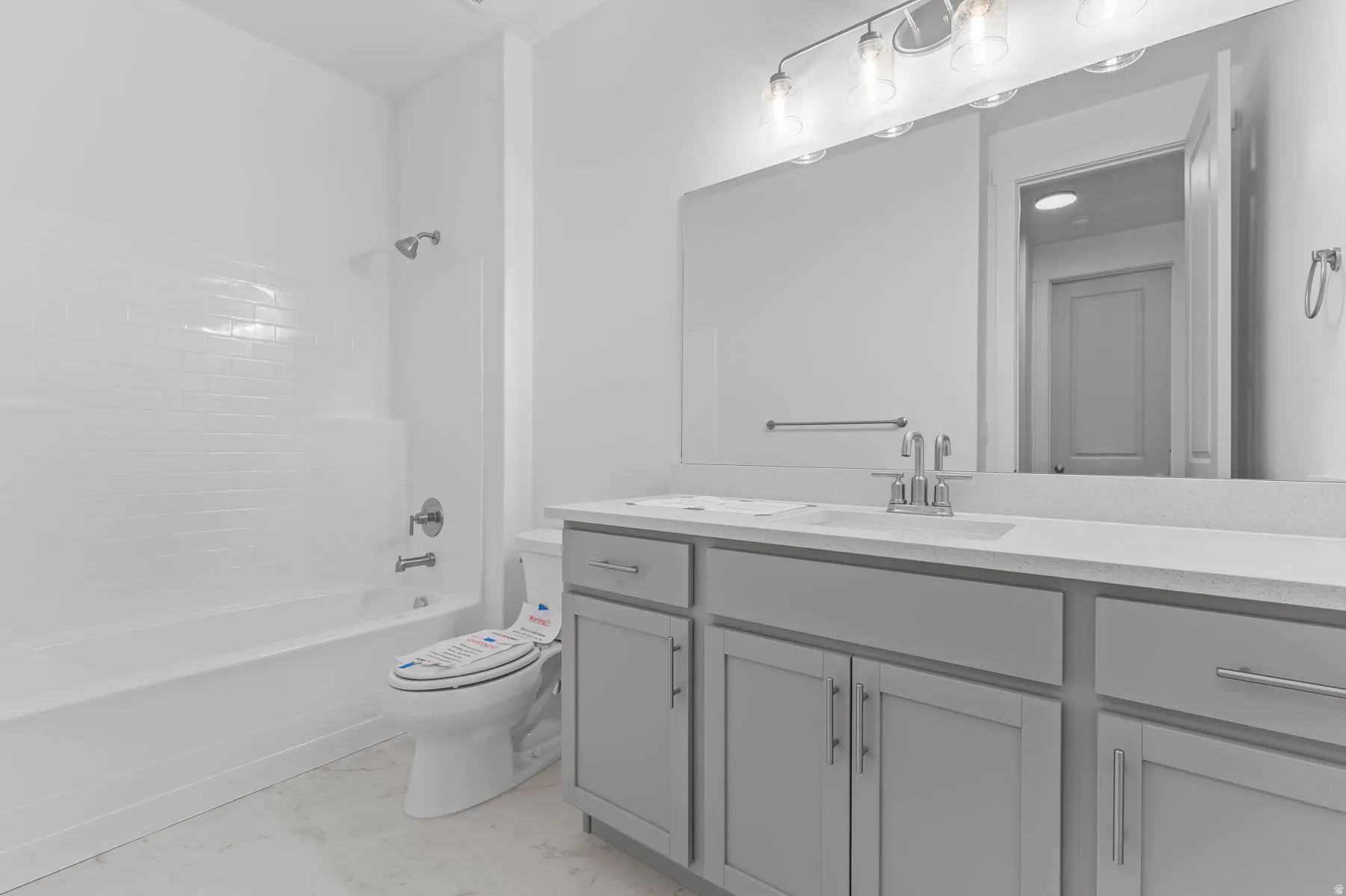 White subway tile shower surround with chrome fixtures, light gray vanity with multiple storage cabinets, light countertop, and a large wall-mounted mirror