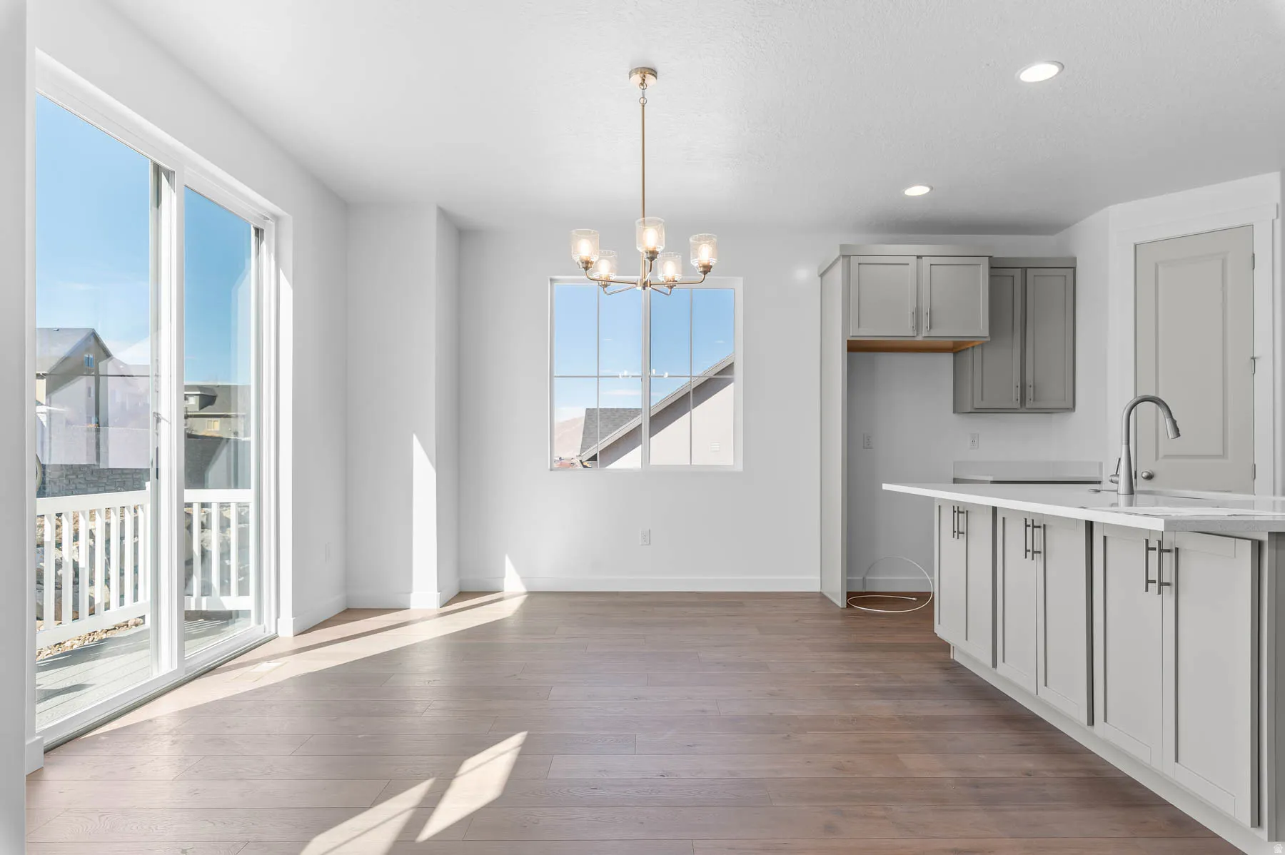 Spacious room featuring wood-finish flooring, a contemporary chandelier, recessed lighting, and a sliding glass door to an outdoor deck