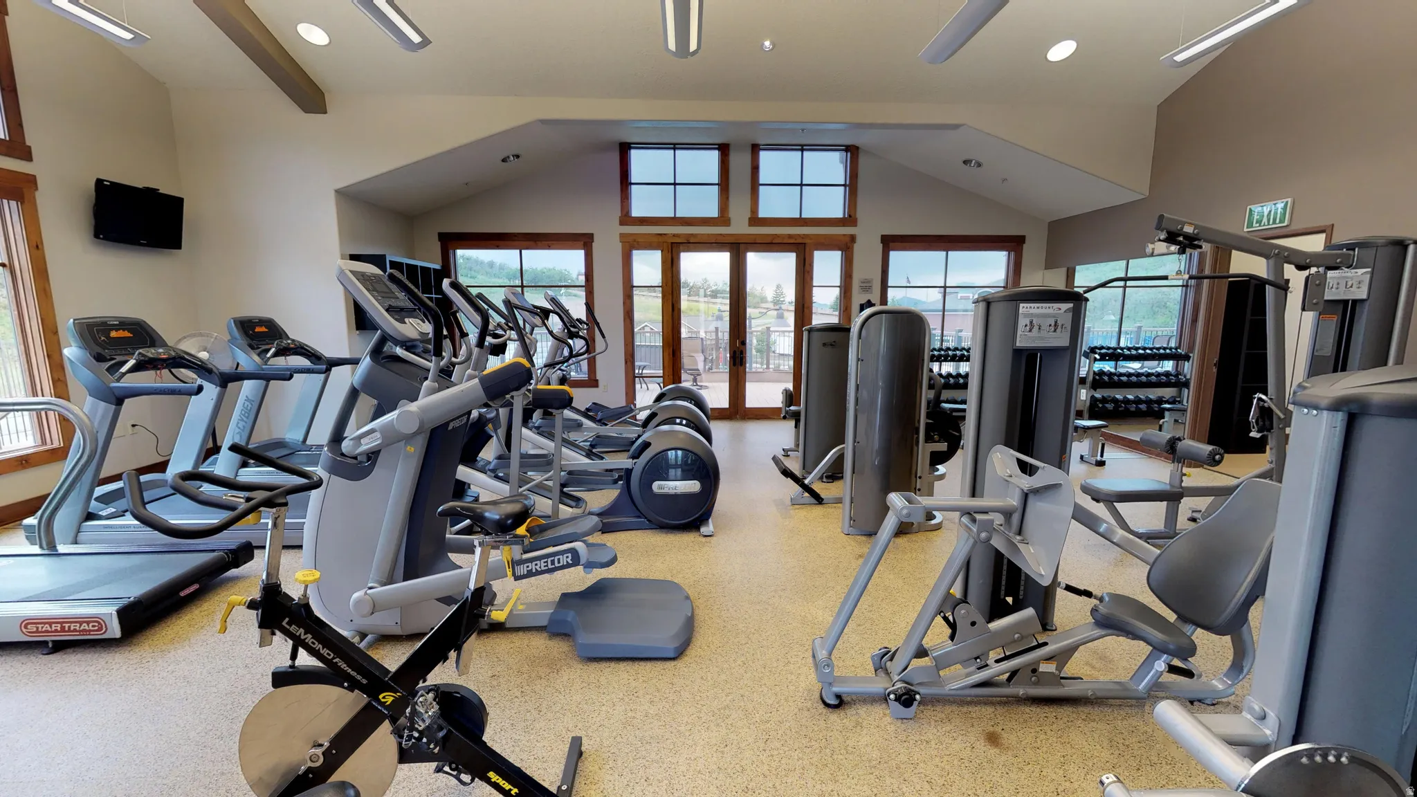 Fitness center featuring exercise equipment, vaulted ceilings, and natural light