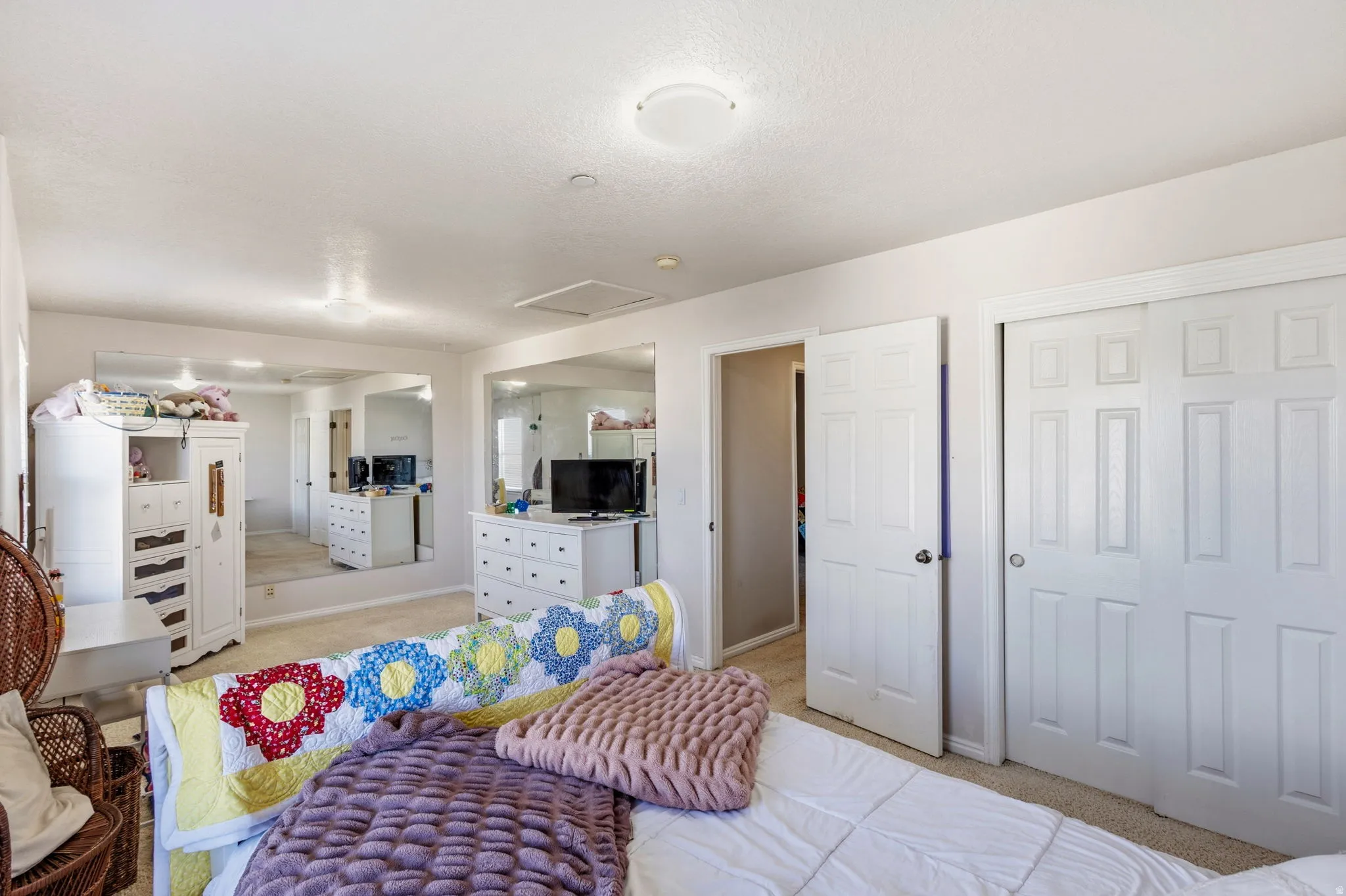 Wall-to-wall carpeting with multiple built-in mirrored walls, a white paneled door, and a white sliding closet door