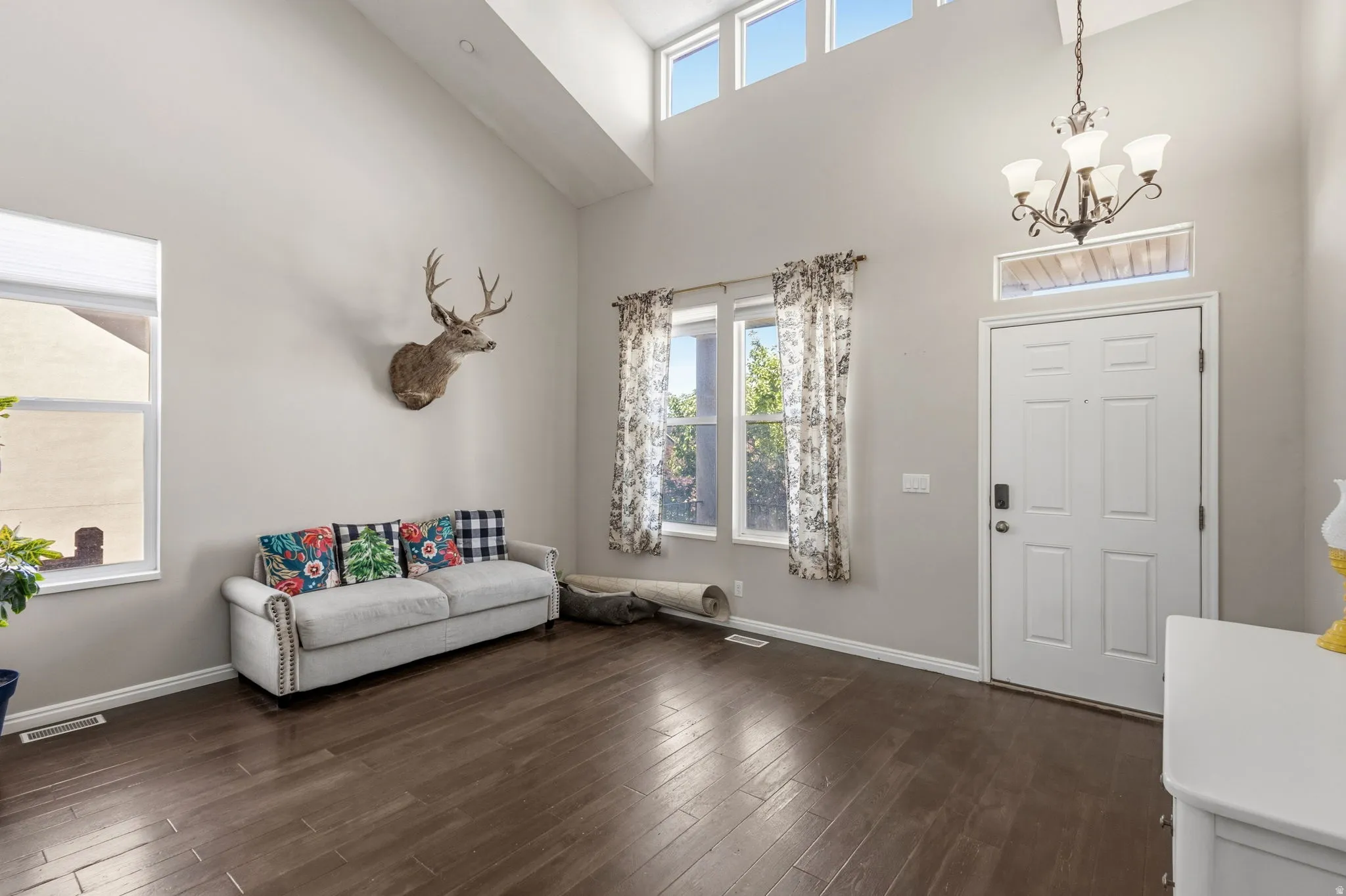 Vaulted ceiling, high transom windows, wood-finish flooring, and chandelier