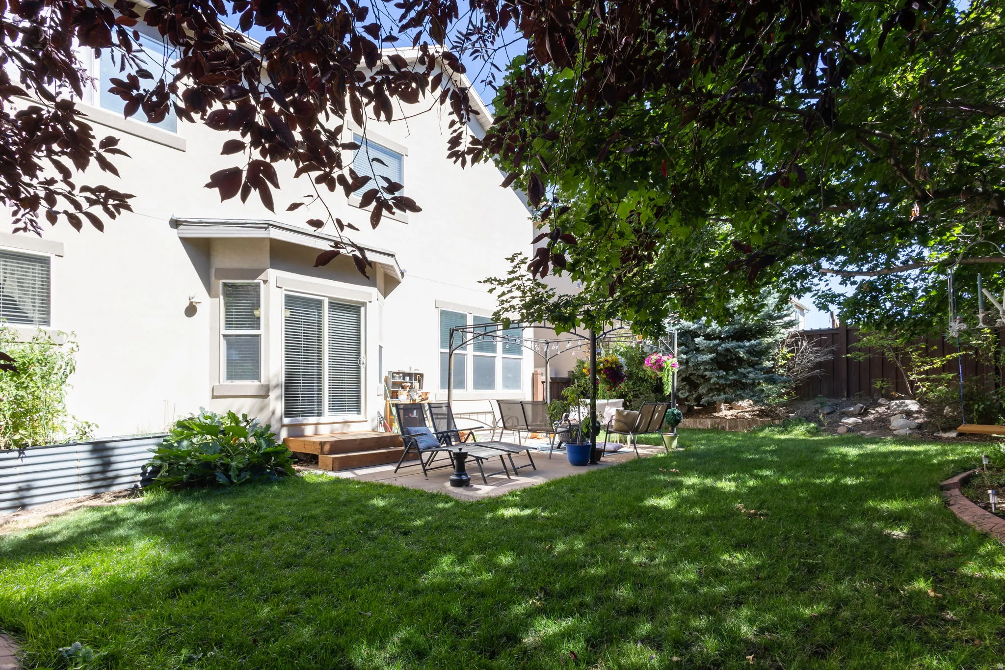 Expansive backyard with a lush lawn, concrete patio, and mature trees