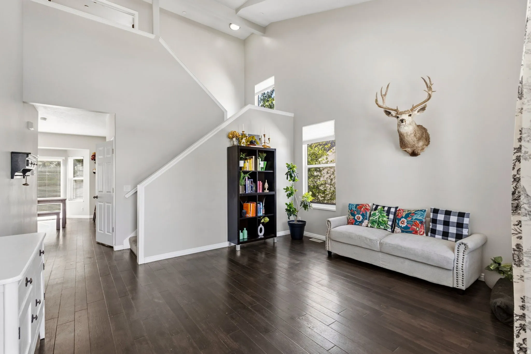 High ceilings, wood-finish flooring, staircase with white railing, built-in shelving, and transom window
