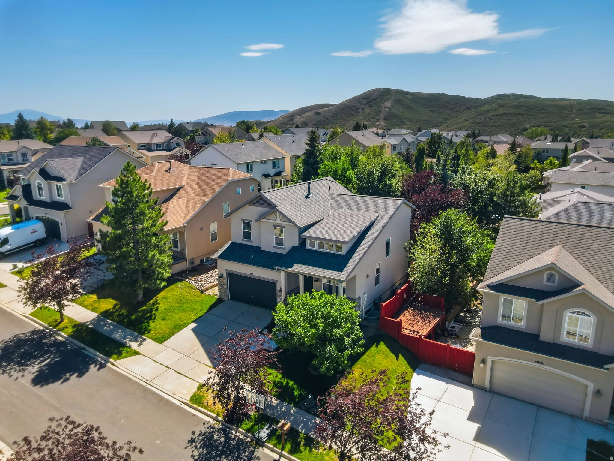 Two-story stucco exterior with a gray shingle roof, attached two-car garage, front yard landscaping, and paved driveway