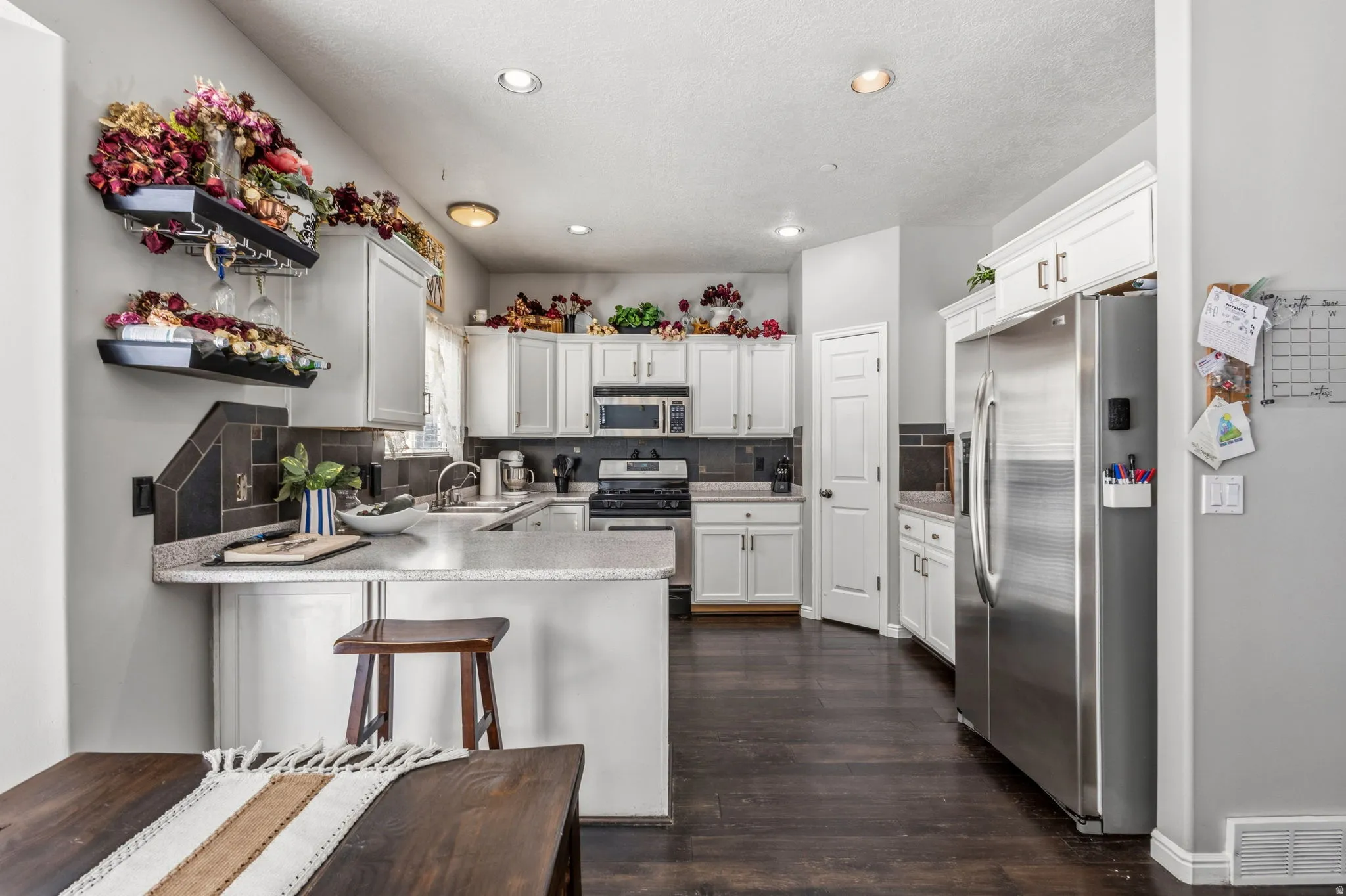 Kitchen featuring white cabinetry, dark wood-finish flooring, recessed lighting, and stainless steel appliances