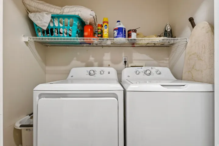 Laundry area featuring a side-by-side washer and dryer, along with a wire storage shelf