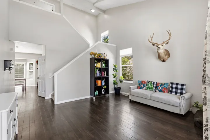 High ceilings, wood-finish flooring, staircase with white railing, built-in shelving, and transom window