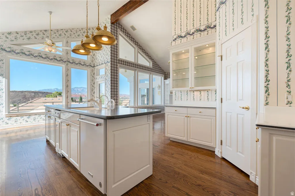 Kitchen island with integrated sink, pendant lighting, built-in display cabinetry, and wood-finish flooring