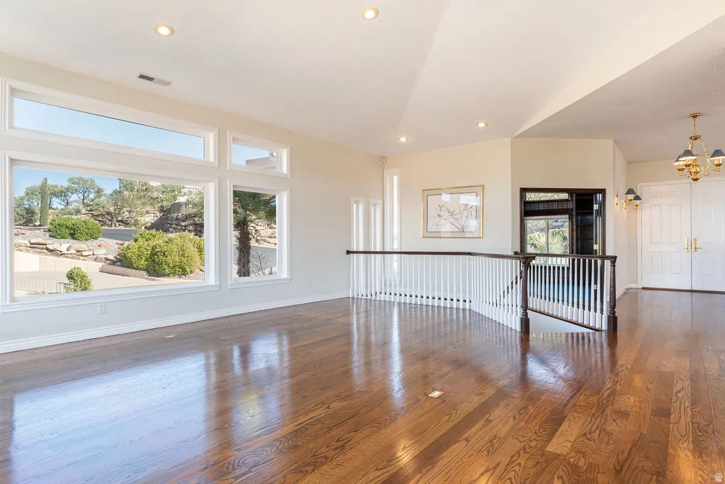 Expansive windows, hardwood flooring, vaulted ceiling, recessed lighting, and a balustrade staircase