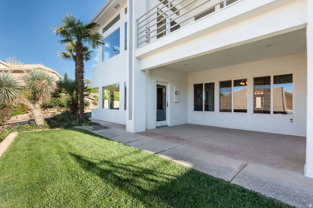 Manicured lawn with a concrete patio, covered outdoor area, and established landscaping