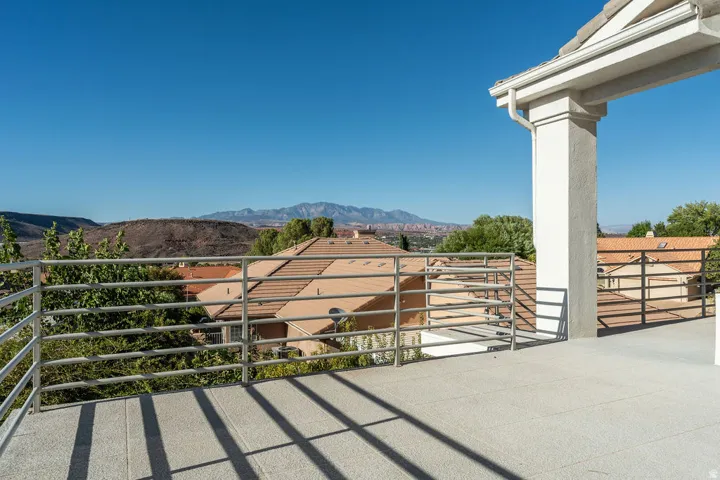 Expansive outdoor terrace featuring a textured concrete surface, sturdy metal railings, and a prominent column supporting an overhang