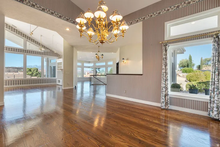 Polished wood-finish flooring, an ornate brass chandelier, and a generously sized window with a deep sill