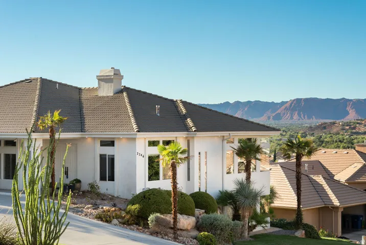 White stucco exterior with a multi-pitch tile roof, featuring a prominent chimney and recessed lighting