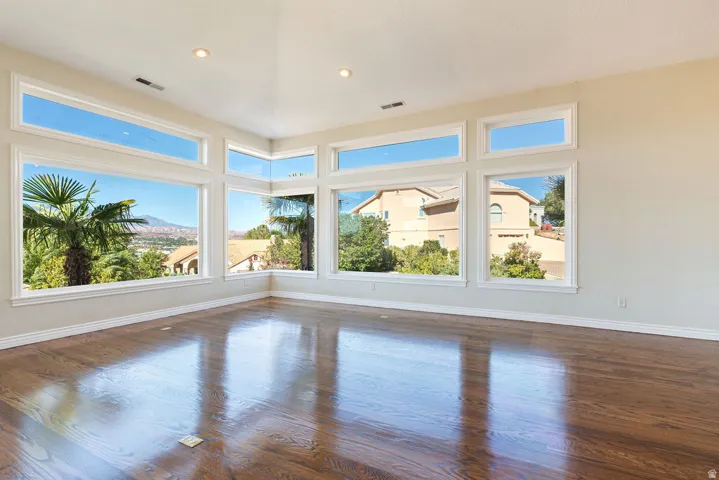 Expansive room featuring rich wood-finish flooring, recessed lighting, and numerous windows