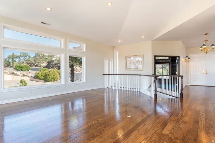 Expansive windows, hardwood flooring, vaulted ceiling, recessed lighting, and a balustrade staircase