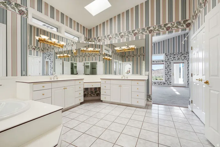 Dual vanities with integrated sinks, white cabinetry, a built-in makeup area, and overhead lighting fixtures