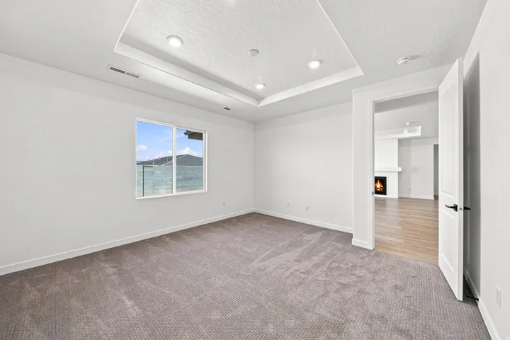 Tray ceiling with recessed lighting, wall-to-wall carpeting, and a window with mountain scenery