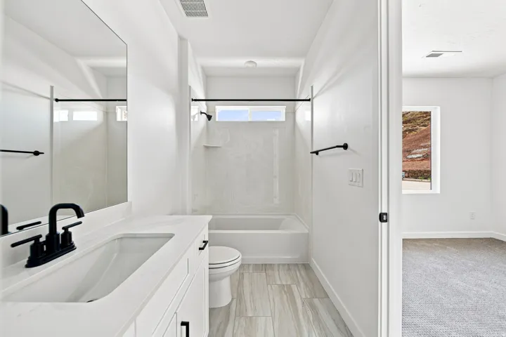 White vanity with an integrated sink, matte black faucet, and rectangular mirror