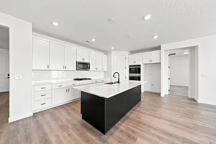 Kitchen featuring white cabinetry, a large central island with a sink, stainless steel appliances, wood-finish flooring, and recessed lighting