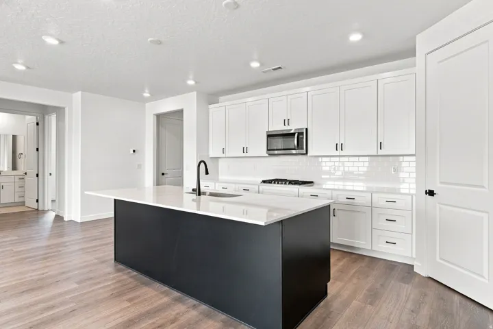 Contemporary kitchen featuring white cabinetry, a large central island with a contrasting base, wood-finish flooring, and recessed lighting