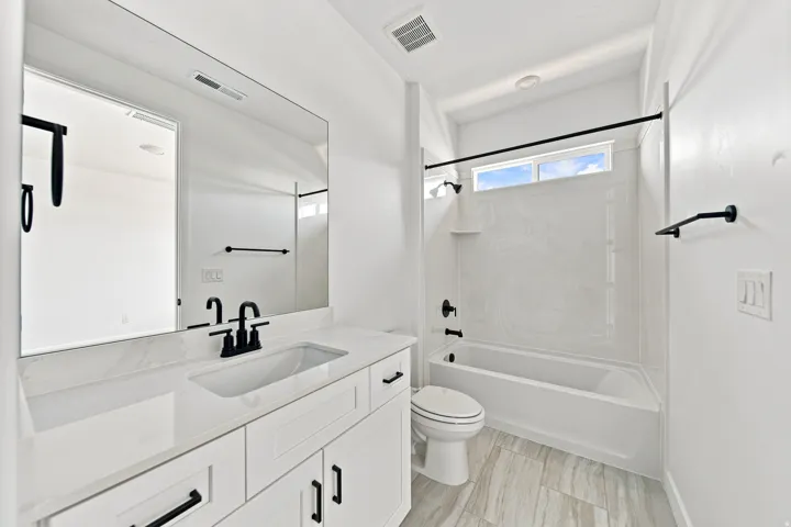 White vanity with integrated sink, black matte fixtures, and a large wall-mounted mirror