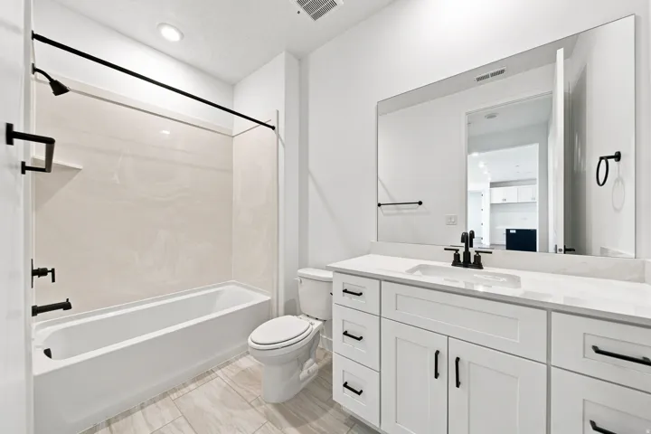 White shaker-style vanity with a light-toned countertop, integrated rectangular sink, and matte black fixtures