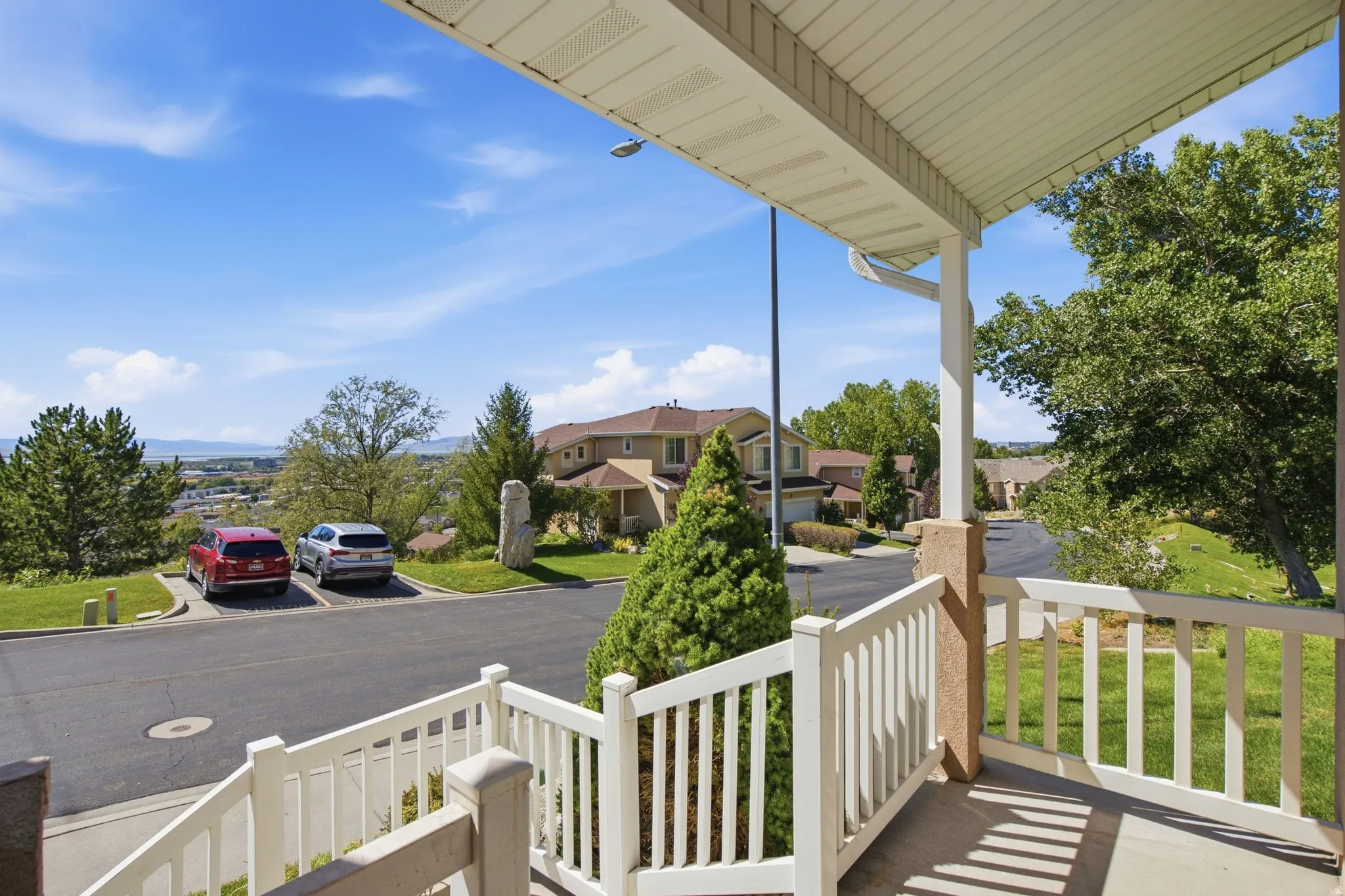 Covered outdoor porch with white railing, textured pillar, and concrete flooring