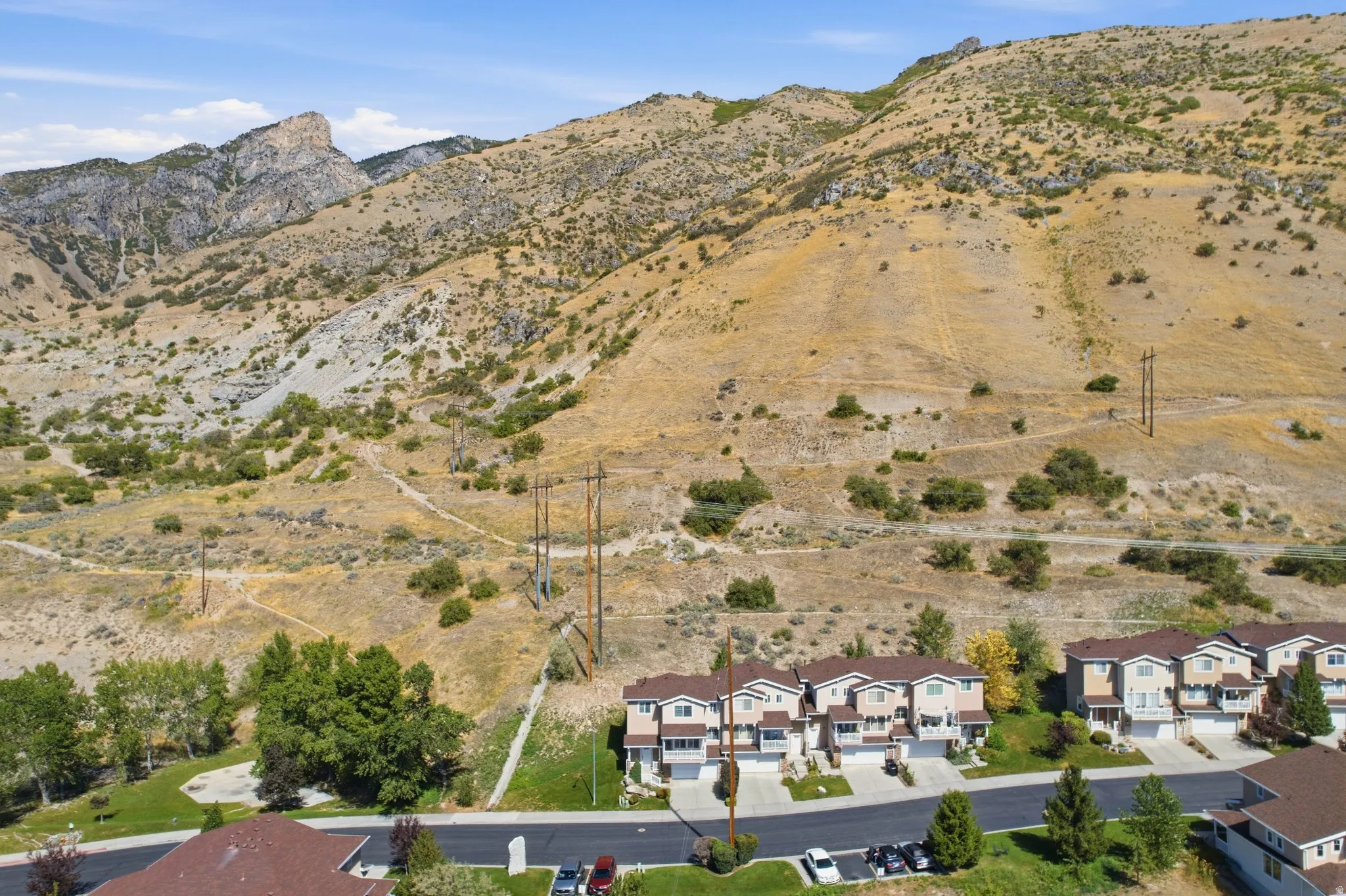 Terraced residential development with mountain backdrop, featuring multi-story townhomes with attached garages and paved driveways