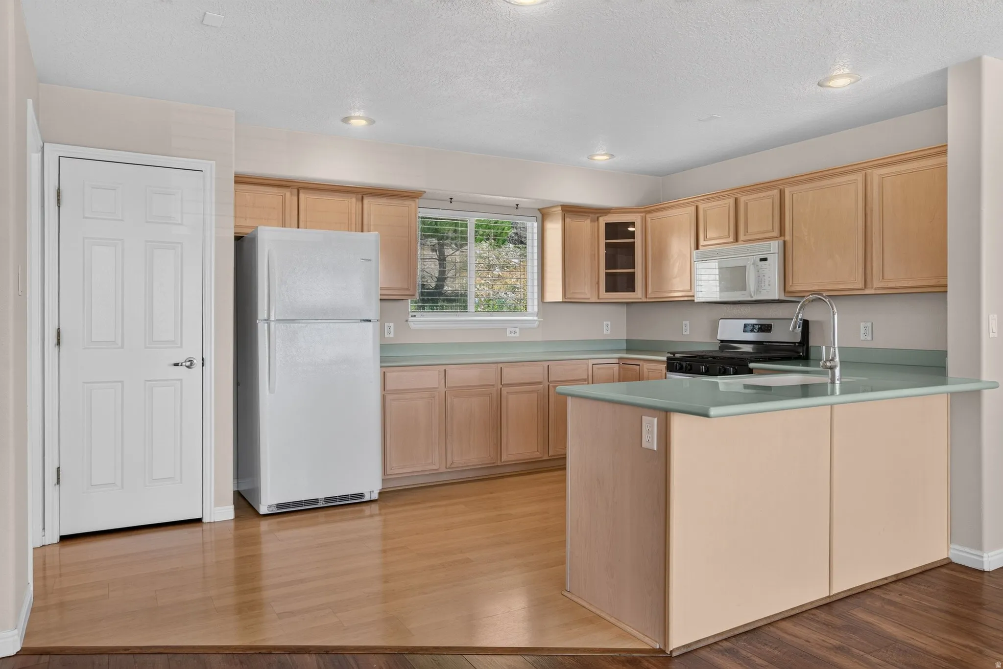 Kitchen featuring wood-finish flooring, light wood cabinetry, a central island with countertop, and recessed lighting