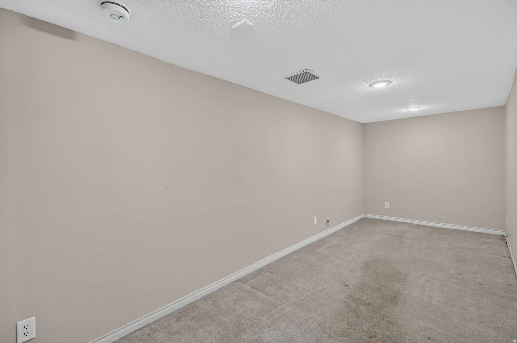 Recessed lighting, textured ceiling, light-colored carpeting, and light-toned wall paint