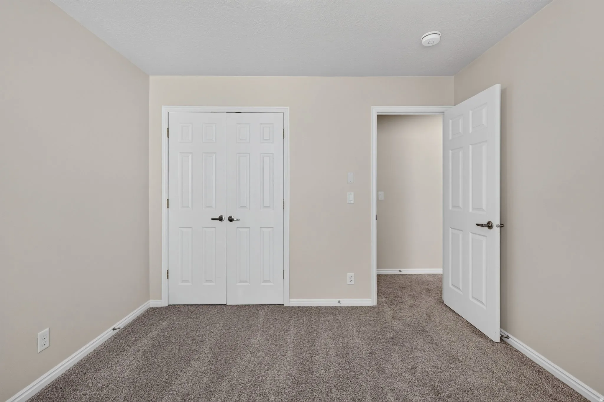 Neutral tone wall paint, textured carpet flooring, white trim, and white paneled doors