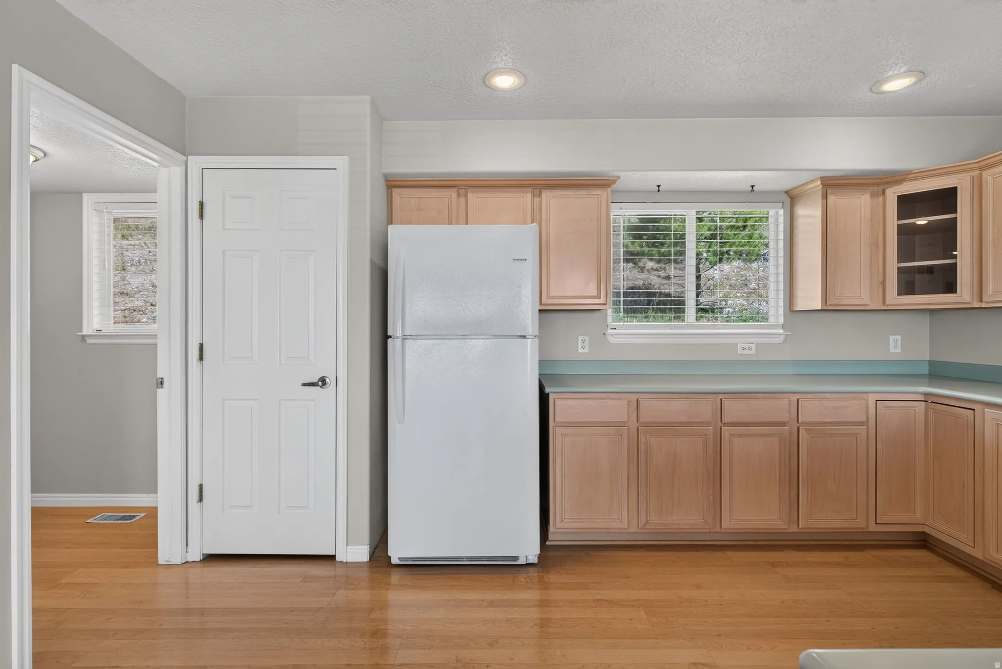 Wood-finish flooring, recessed lighting, wood cabinetry, and a window with blinds