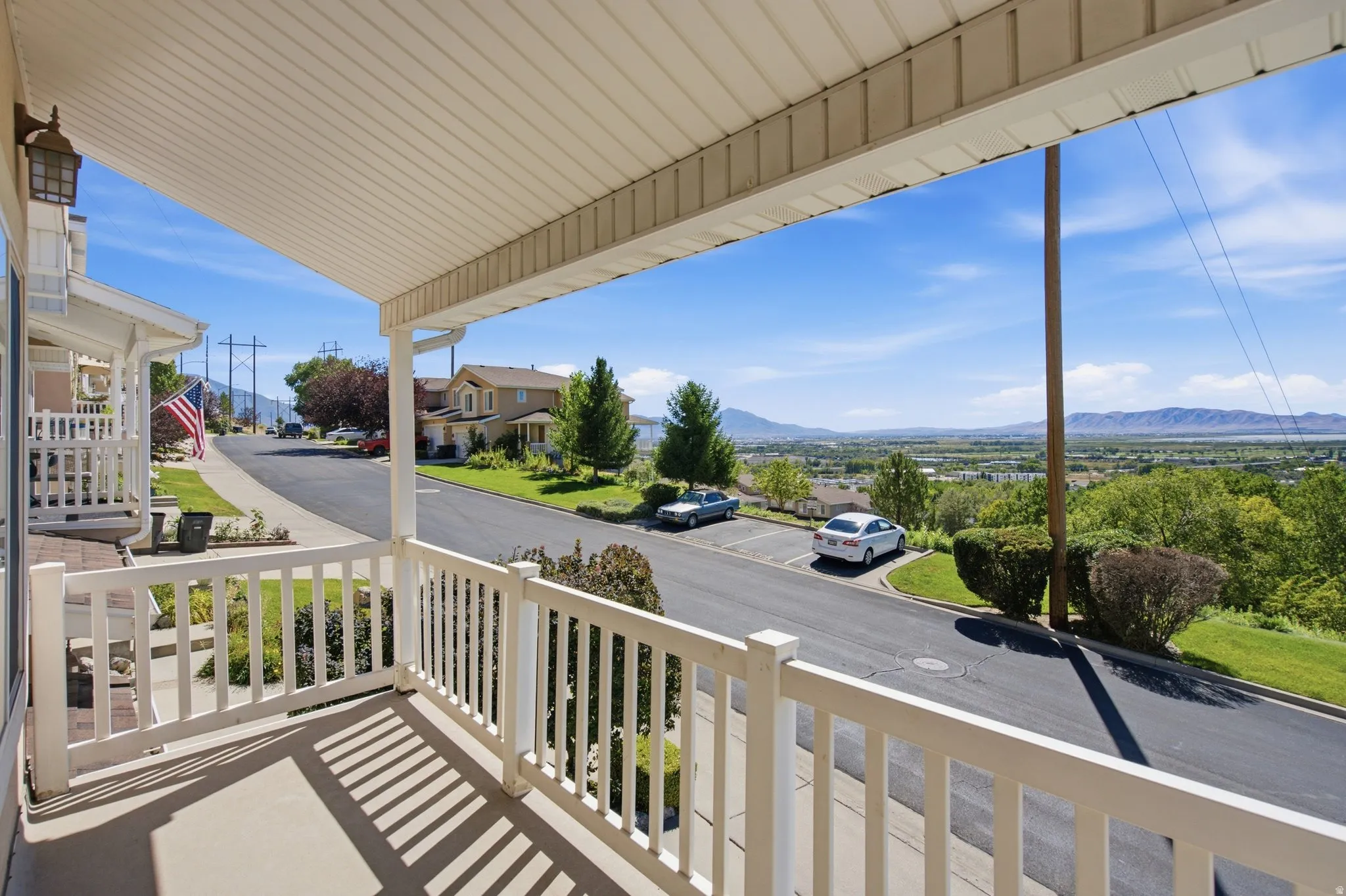 Covered front porch with white railings and a concrete floor