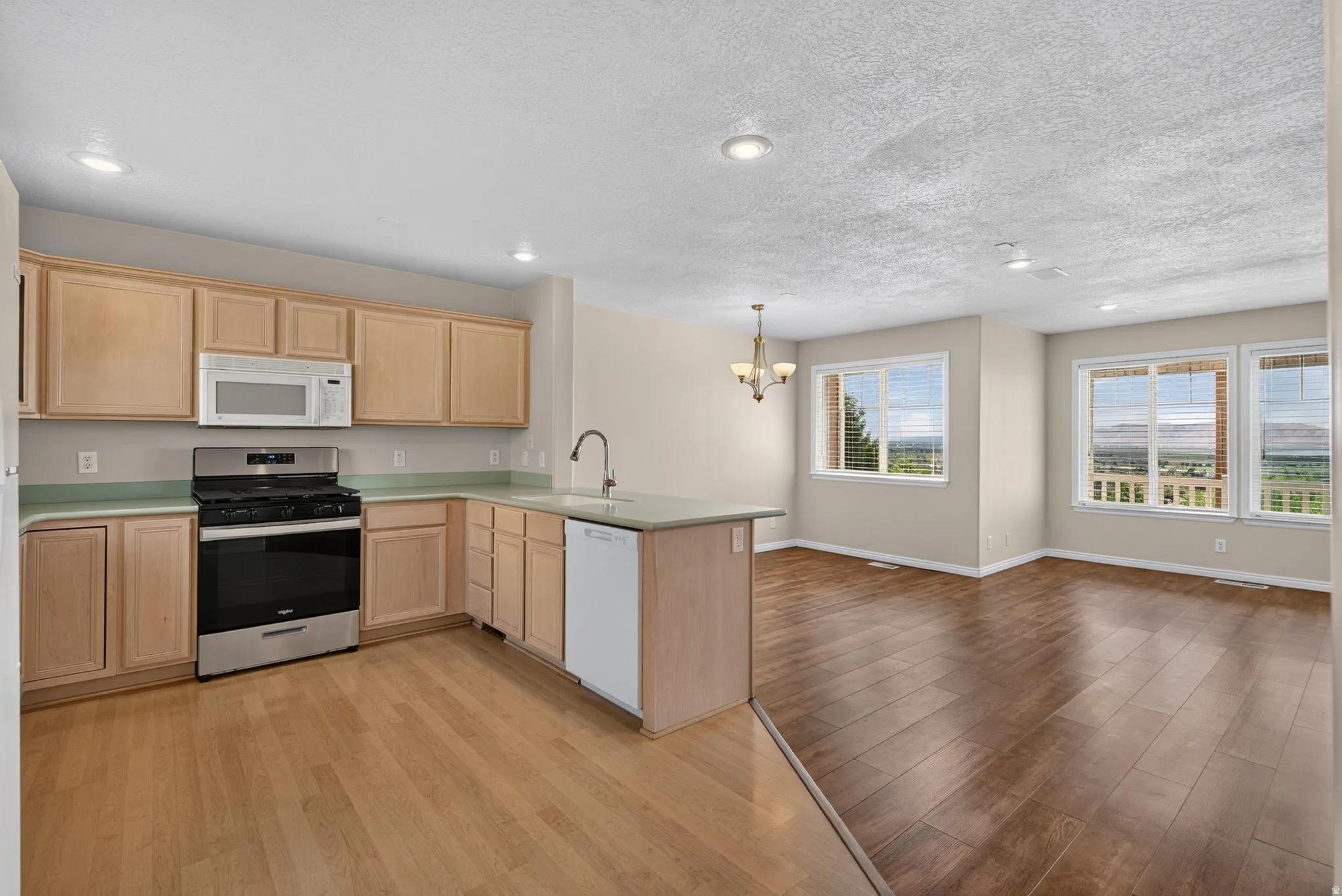 Kitchen featuring wood-finish cabinetry, stainless steel appliances, and a peninsula with integrated sink
