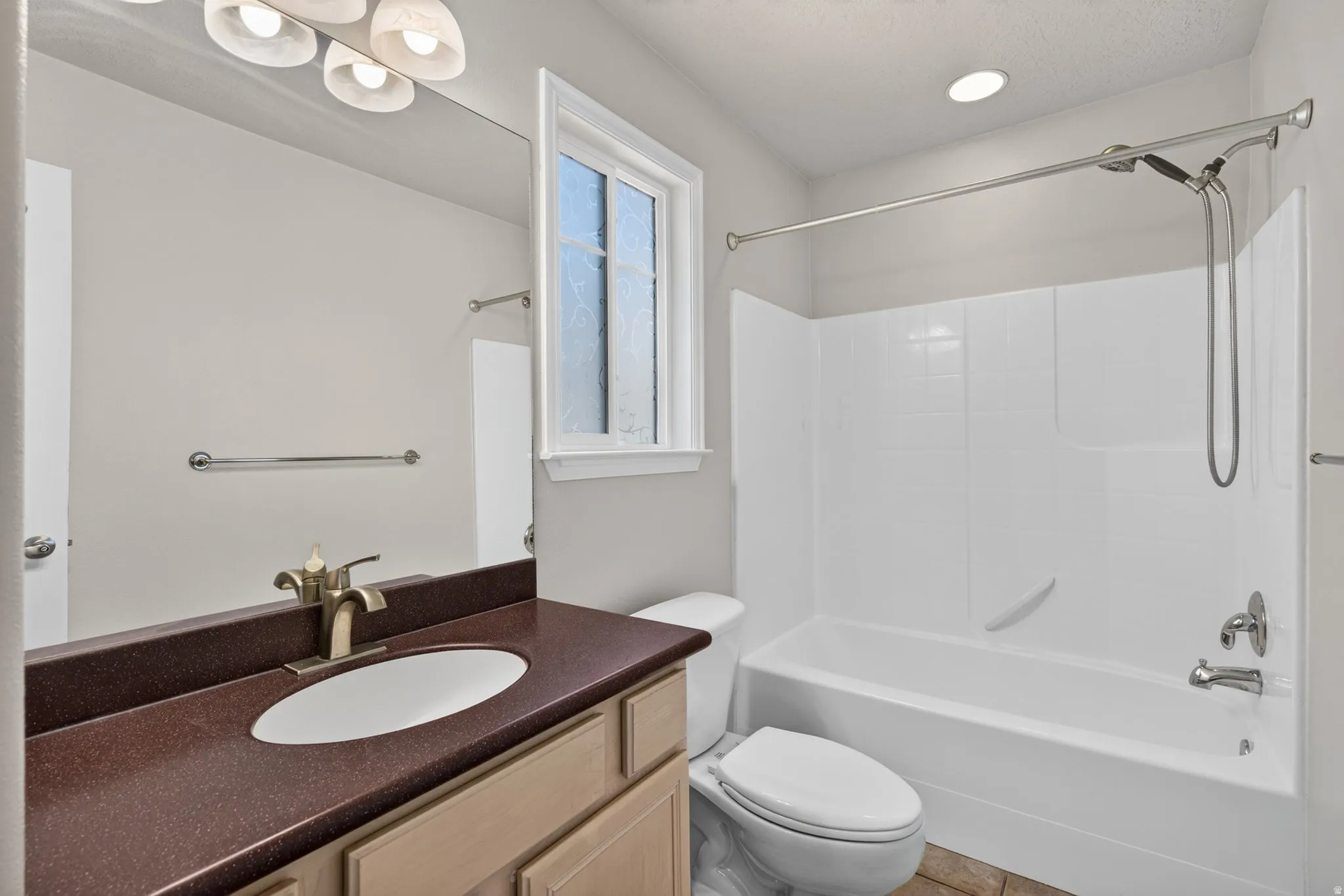 Vanity with an oval undermount sink, bronze-finish faucet, and a brown countertop