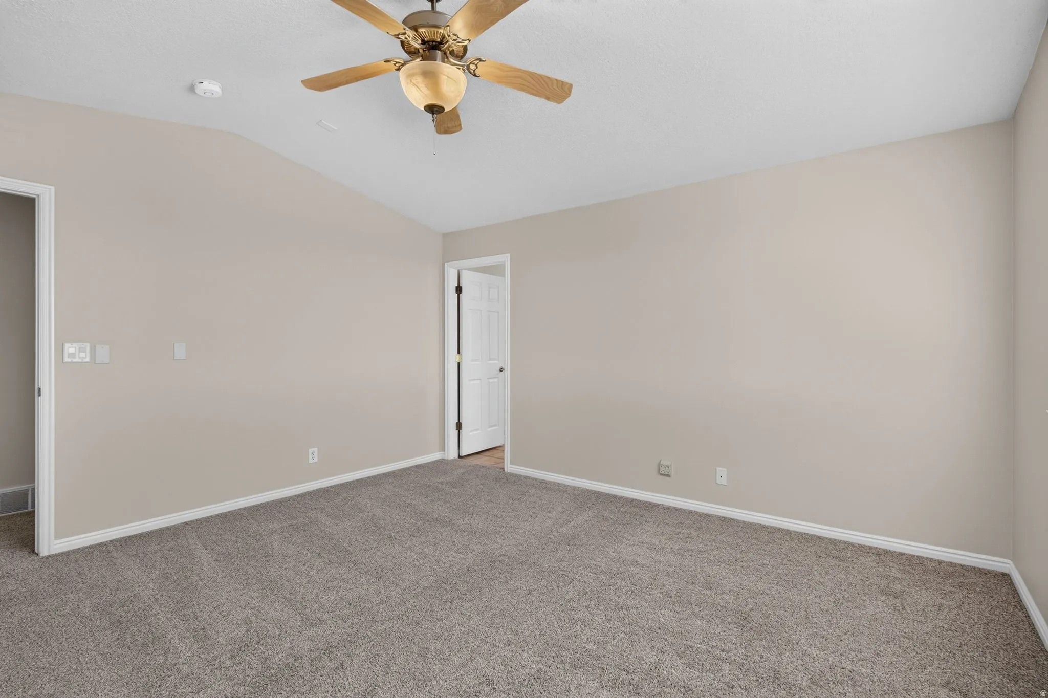 Carpeted room featuring a ceiling fan with light fixture and light-colored walls